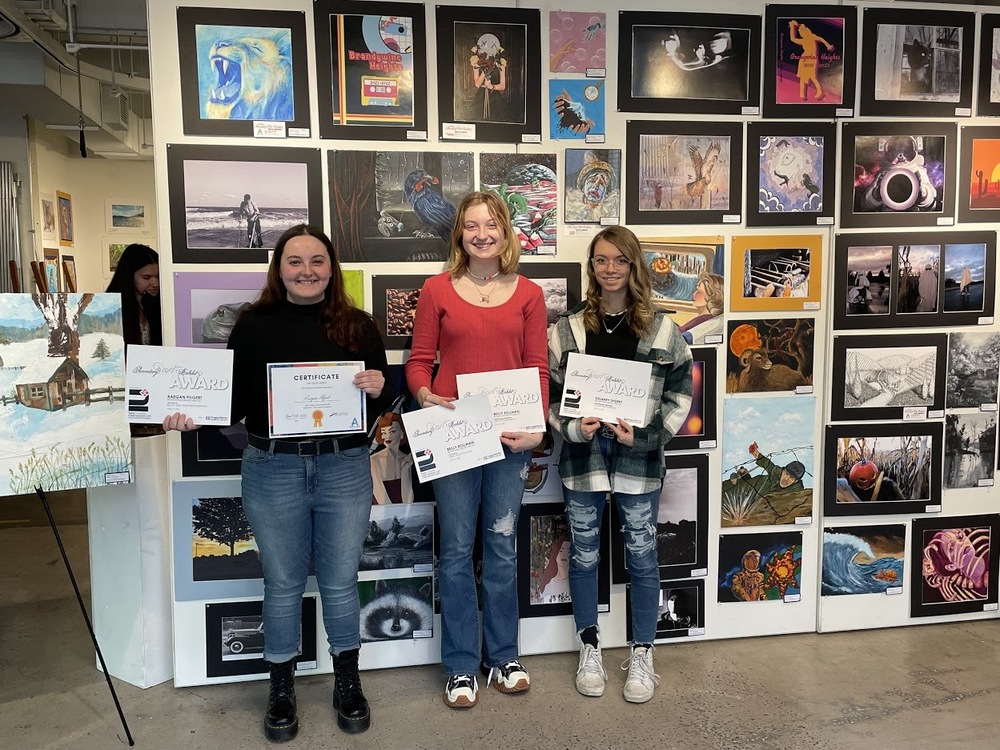 Three students display their art awards