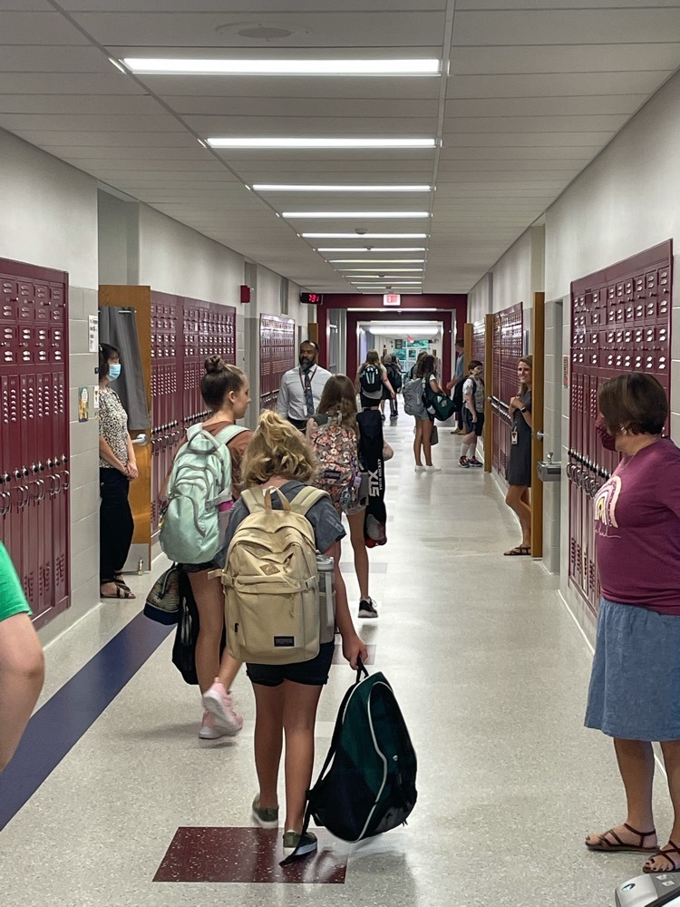 Teachers greet students and assist as they look for their homerooms.