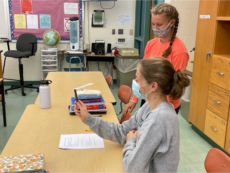 two students measure humidity using a sling psychrometer.