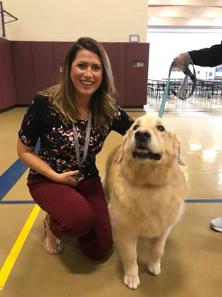 Ms. Kelly poses with a reading support dog.