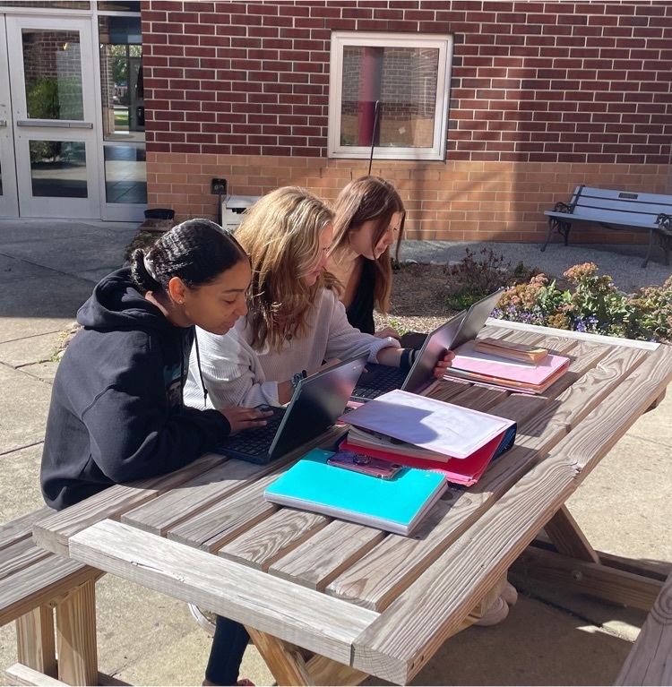 students work at a picnic table in the courtyard.